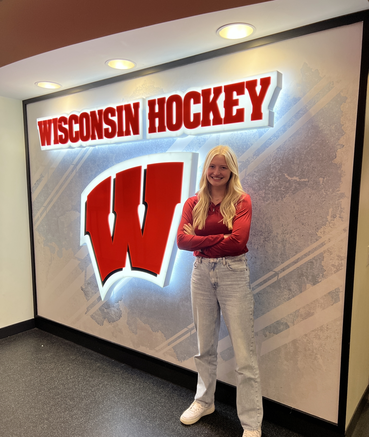 Taylor in front of a Wisconsin Hockey sign